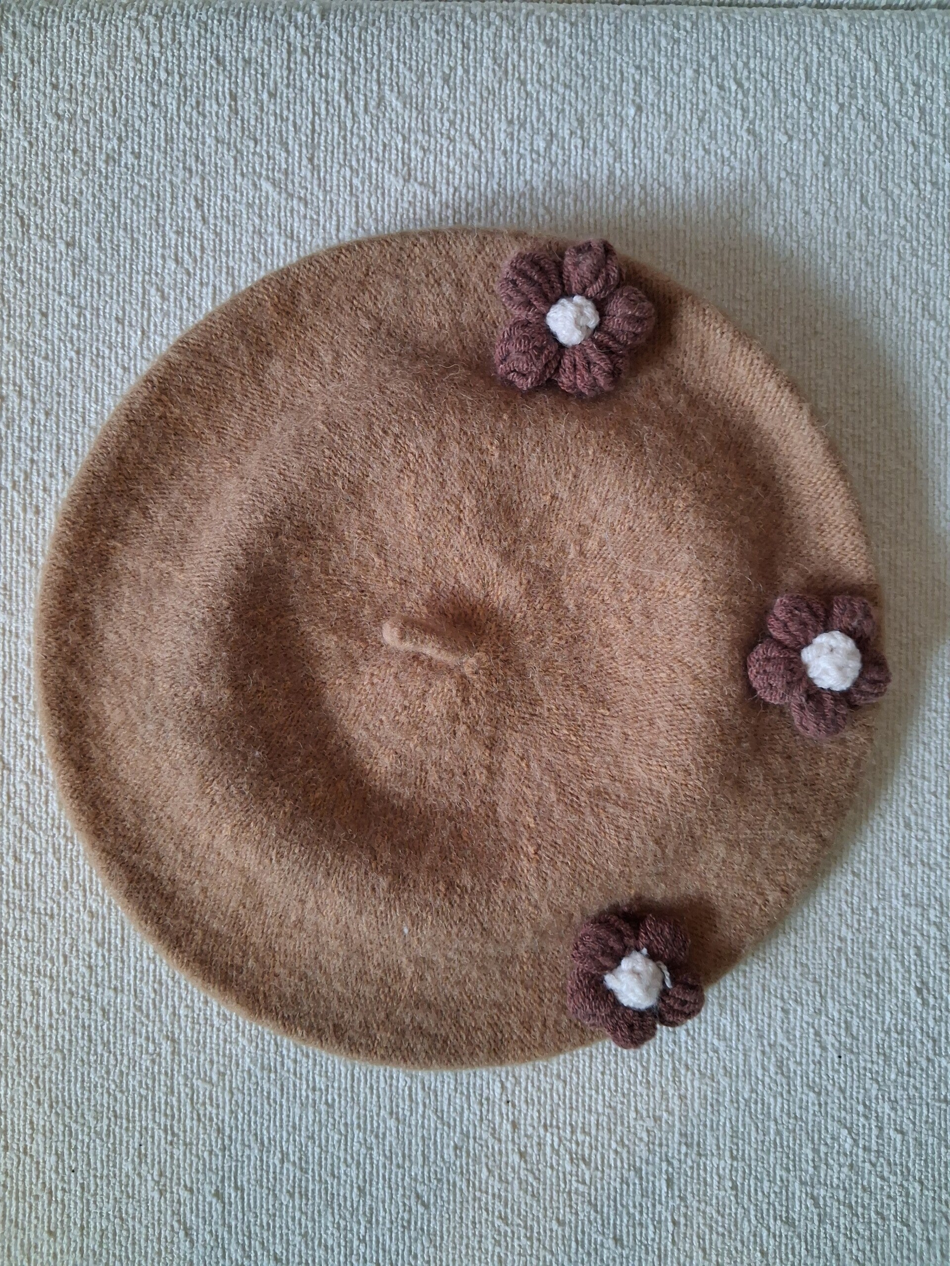 Camelkleurige baret met bloemetjes.
