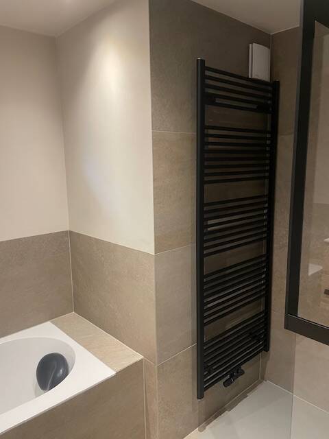 Designradiator in mat zwart naast ligbad en Nobili wc – badkamer door J. Wuyts Loodgieterij
