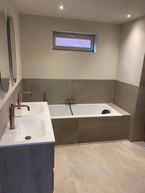 Sanitaire installatie met inloopdouche, wastafel en mat-zwarte radiator – professioneel geplaatst