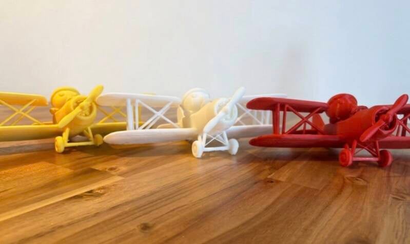 Gele, witte en rode 3D-vliegtuigjes van MEM Airlines op een houten tafel