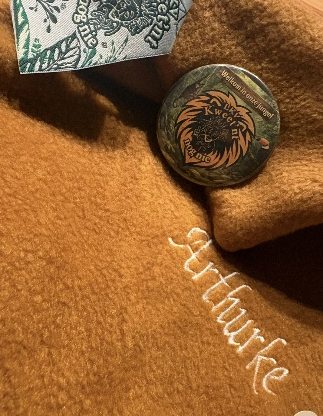 Detail van gepersonaliseerde poncho en verenigingsbadge