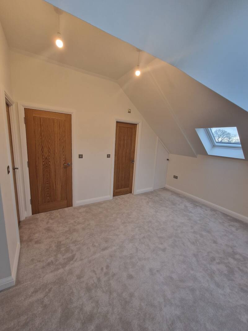 Oxted builder – completed loft room with roof window, timber doors and fitted carpet