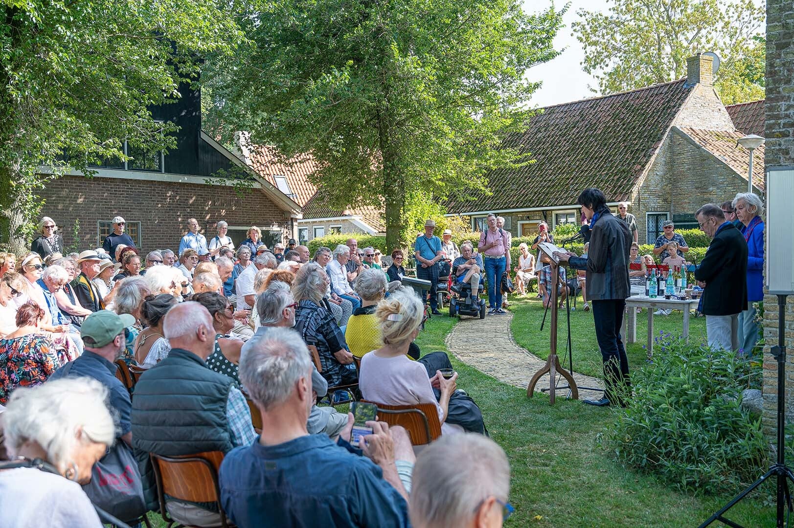 Haas leest uit werk van Reve. Bij de 20e herdenking op 15 augustus 2025. Op de achtergrond Huize het Gras. Foto: Hans Nooitgedagt