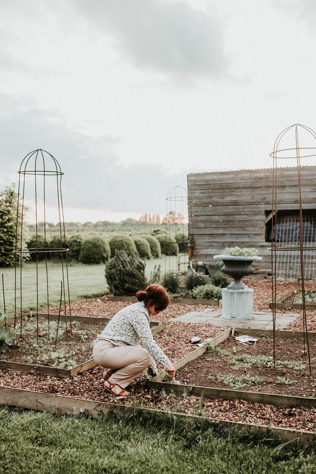 Vrouw hurkt in moestuin en werkt met bloemenschepje in de aarde. Grond voorbereiden bij tuinieren in februari