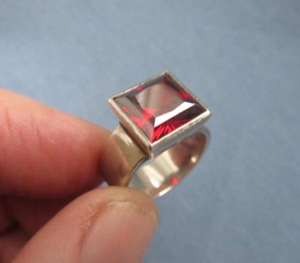 Zilveren ring met rode geslepen steen.