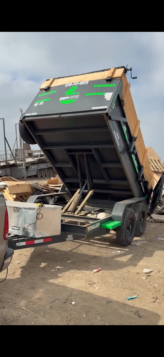 DBM Advanced Junk Hauling dump trailer unloading wooden pallets and construction debris at a site in El Cajon, California.