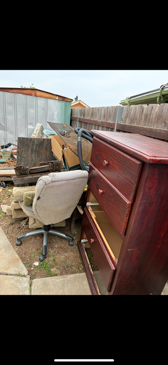 Assorted junk furniture including gray office chair, open wooden dresser, and foam padding ready for removal by DBM Hauling in El Cajon, California.