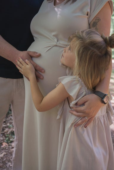 Dochter knuffelt met de zwangere buik van mama