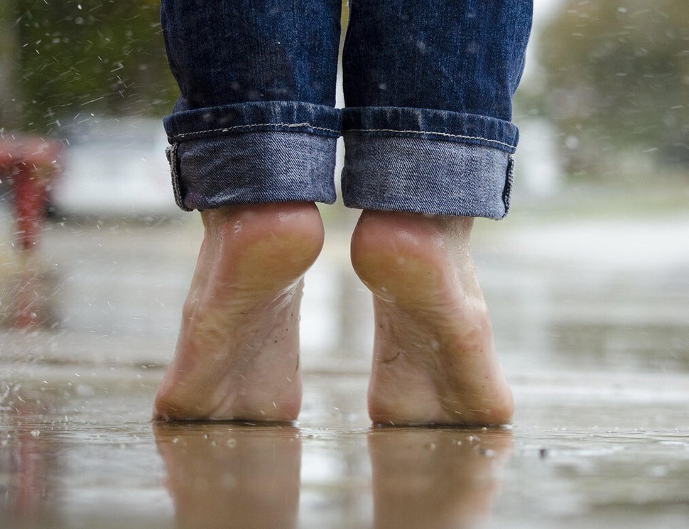 Barfüßige Person mit hochgekrempelten Jeans steht auf nassem Boden, Wasser spritzt um die Füße, im Kontext Blog Jenseitskontakte Jana Lorenz.