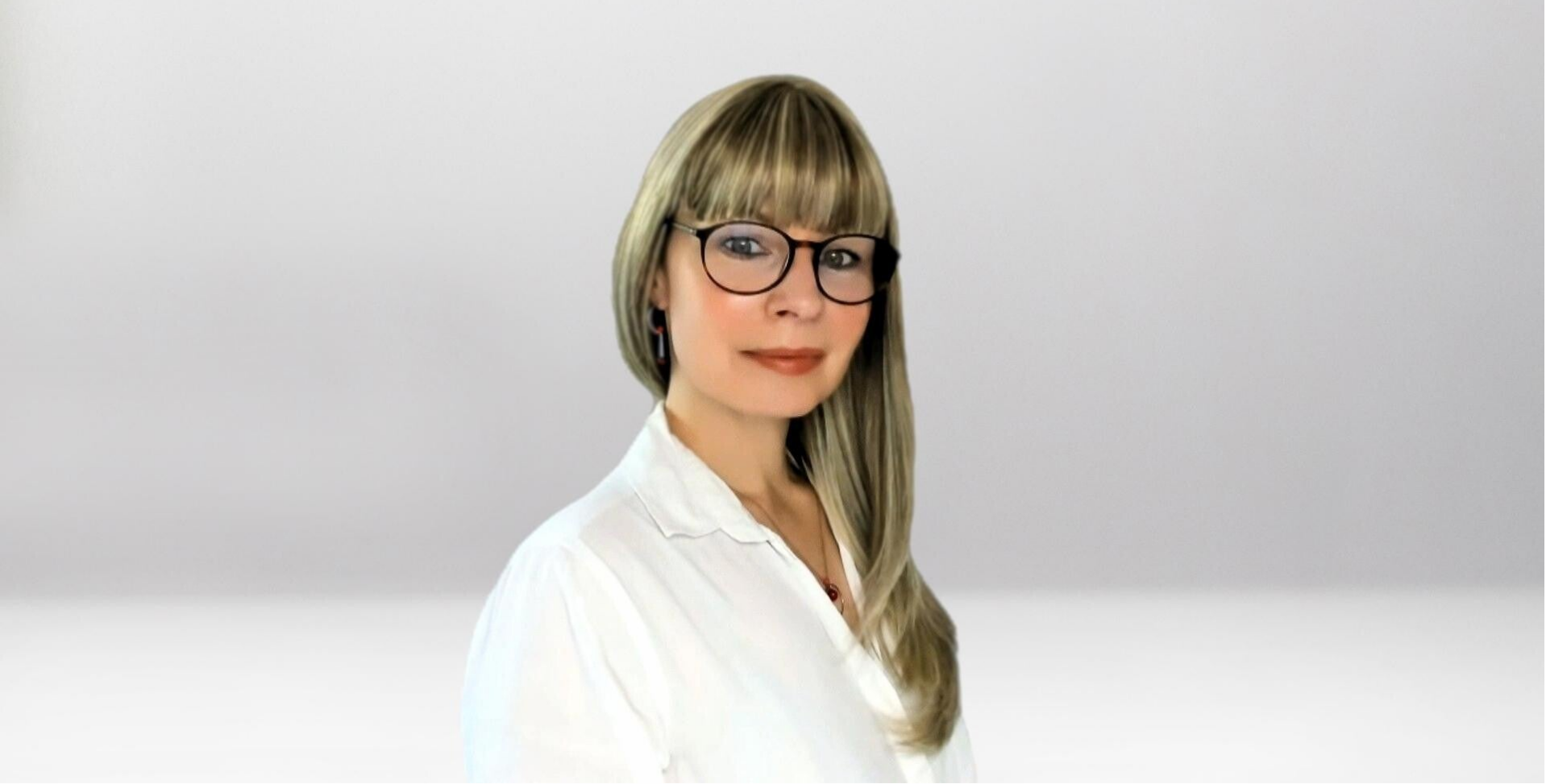 Jana Lorenz mit langen blonden Haaren, trägt weiße Bluse und goldene Ohrringe, Halskette mit rundem roten Anhänger