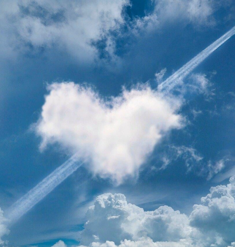 Ein Herz aus Wolken im Himmel, mit einem Flugzeug, das einen Kondensstreifen in Herzform hinterlässt, Kontext Blog Jenseitskontakte Jana Lorenz.