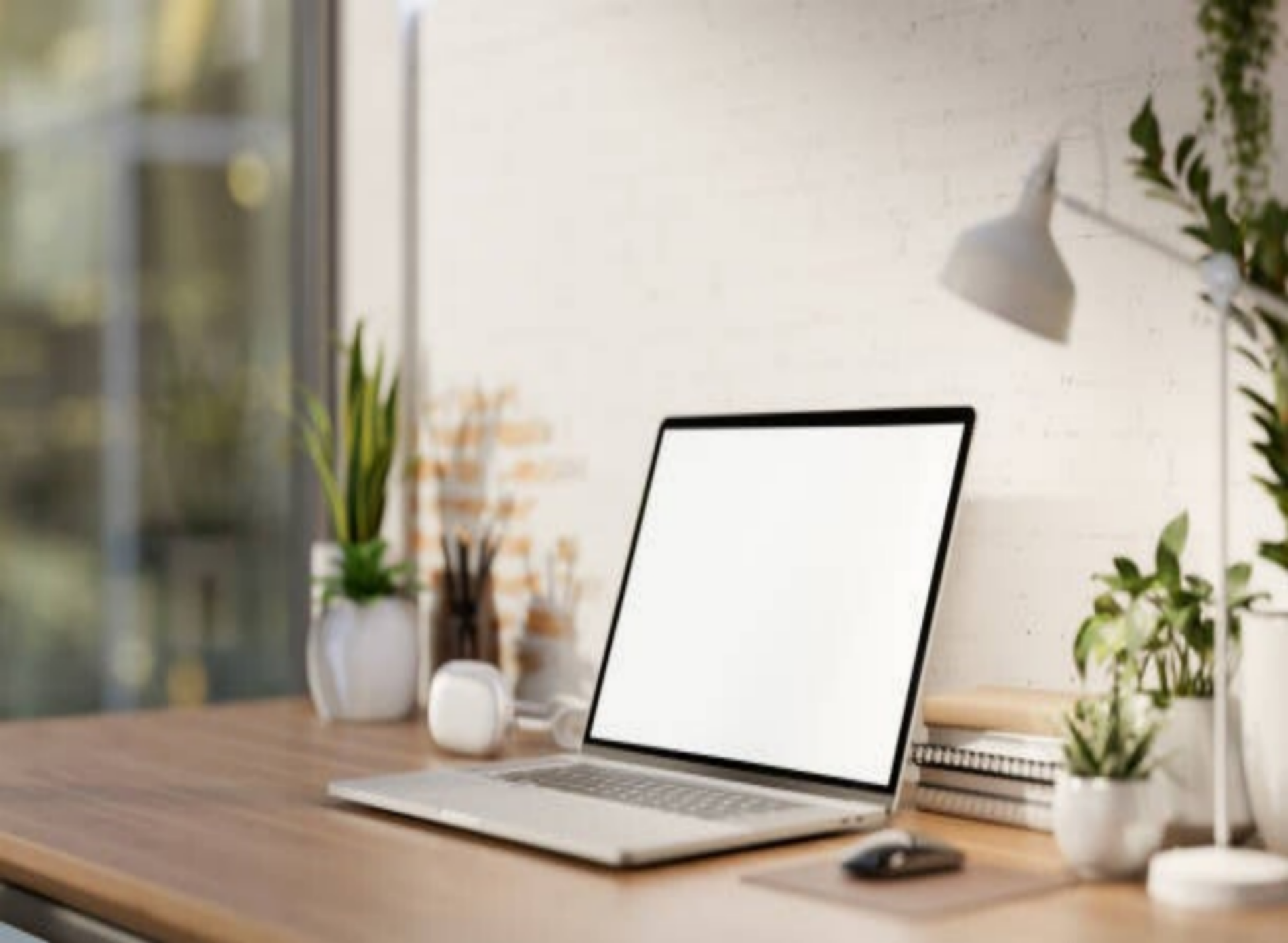 Moderner Arbeitsplatz mit aufgeklapptem Laptop, Schreibtischlampe, mehreren Pflanzen und Notizbüchern auf einem Holztisch, im Kontext mit Jenseitskontakte Jana Lorenz.