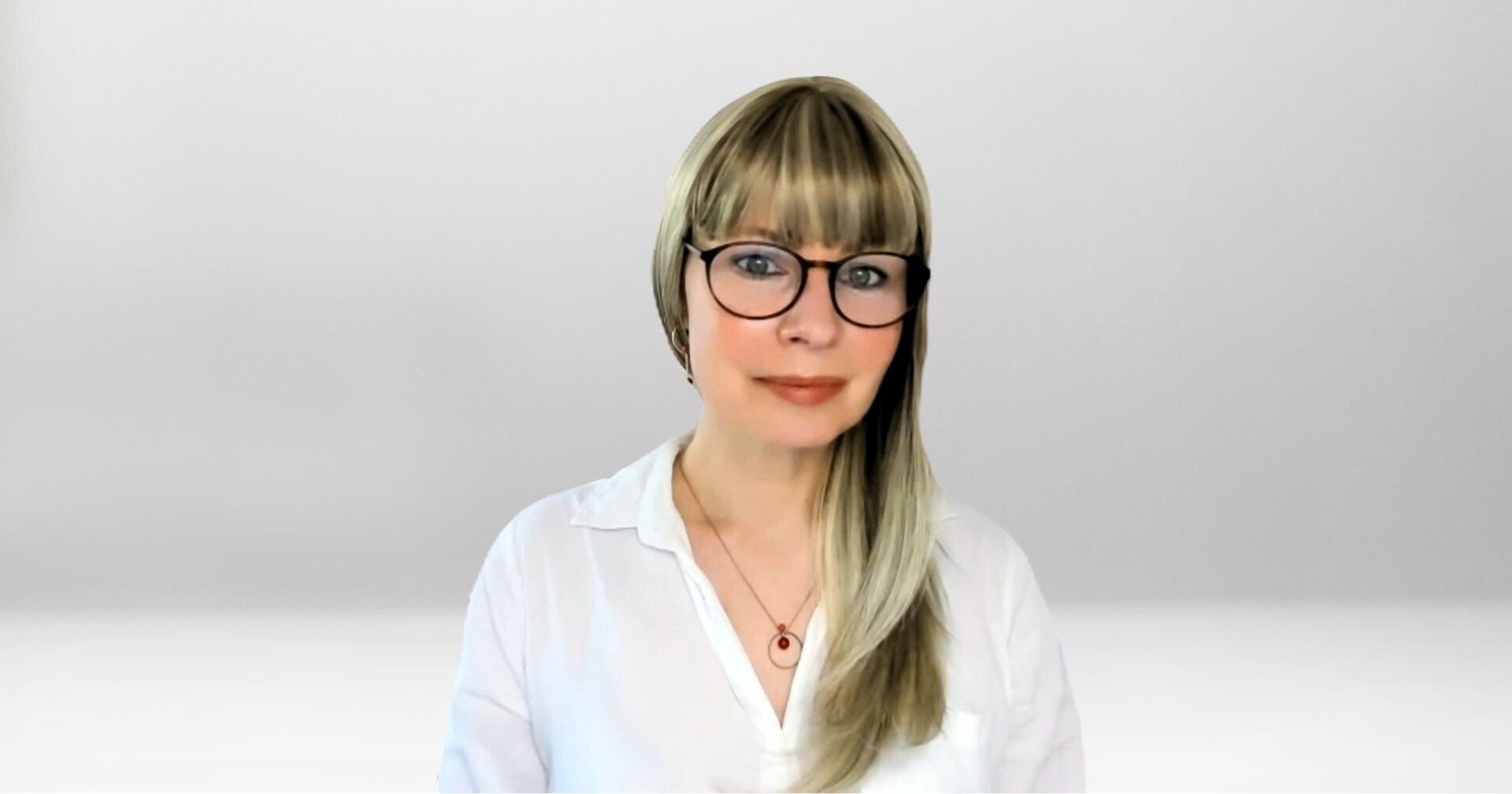 Jana Lorenz mit langen blonden Haaren, trägt weiße Bluse und goldene Ohrringe, Halskette mit rundem roten Anhänger