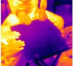 Wärmebild einer Person mit Händen über einem Objekt, das Wärme abstrahlt, in lila und orange Farbtönen, Kontext Blog Jenseitskontakte Jana Lorenz.