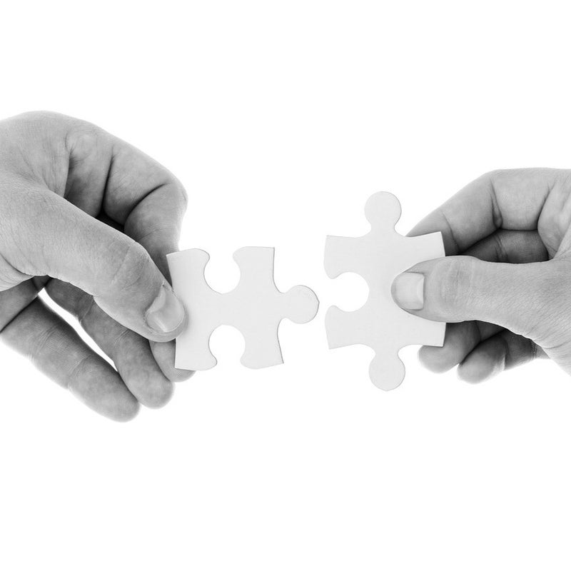 Zwei Hände, die jeweils ein weißes Puzzlestück halten und diese zusammenfügen, symbolisieren Verbindung im Kontext von der kombinierten Sitzung als Jenseitskontakt und Geistführerkontakt mit Medium Jana Lorenz.