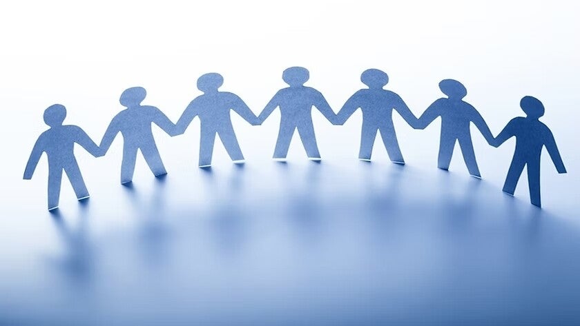 Acht stilisierte, blaue Papiersilhouetten von Menschen, die sich an den Händen halten, auf einer glatten Oberfläche, Blog Jenseitskontakte Jana Lorenz