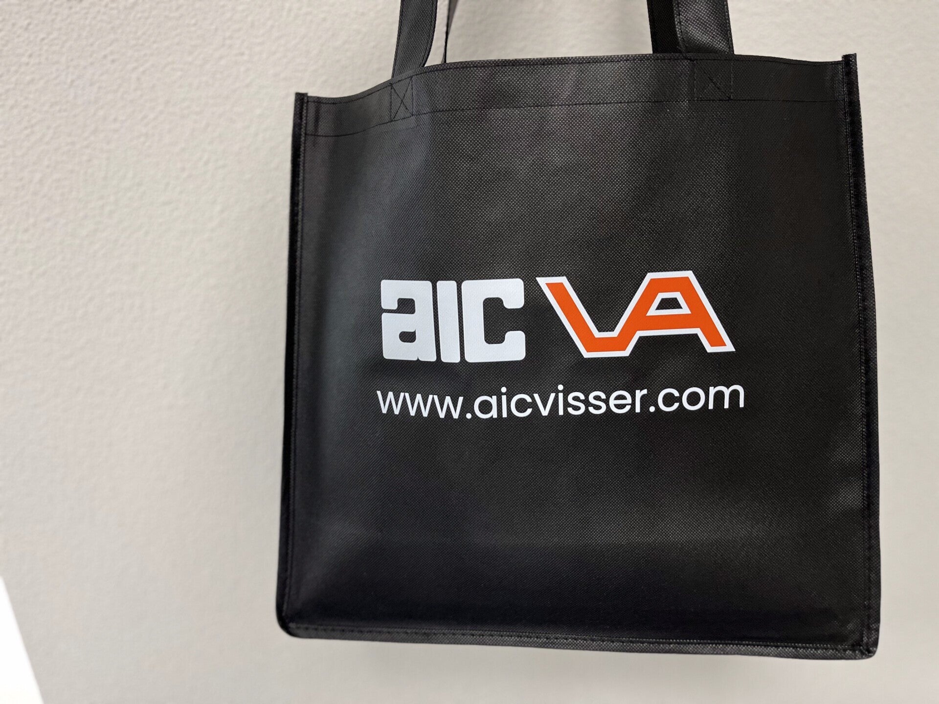 Zwarte tas met het logo van AIC Visser