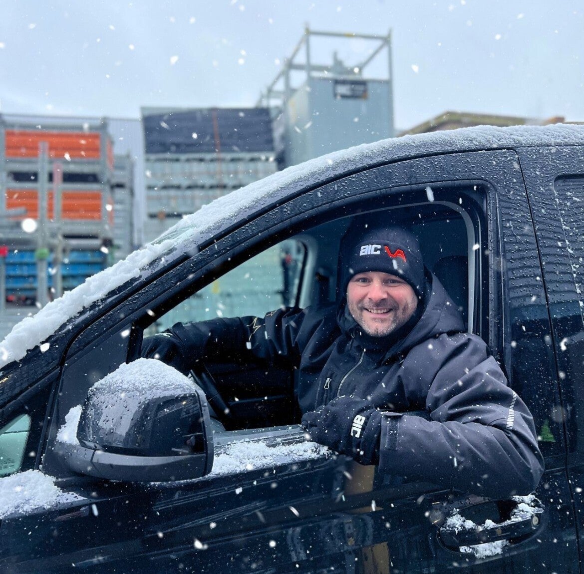 Medewerker van AIC Visser met een muts met logo in de sneeuw