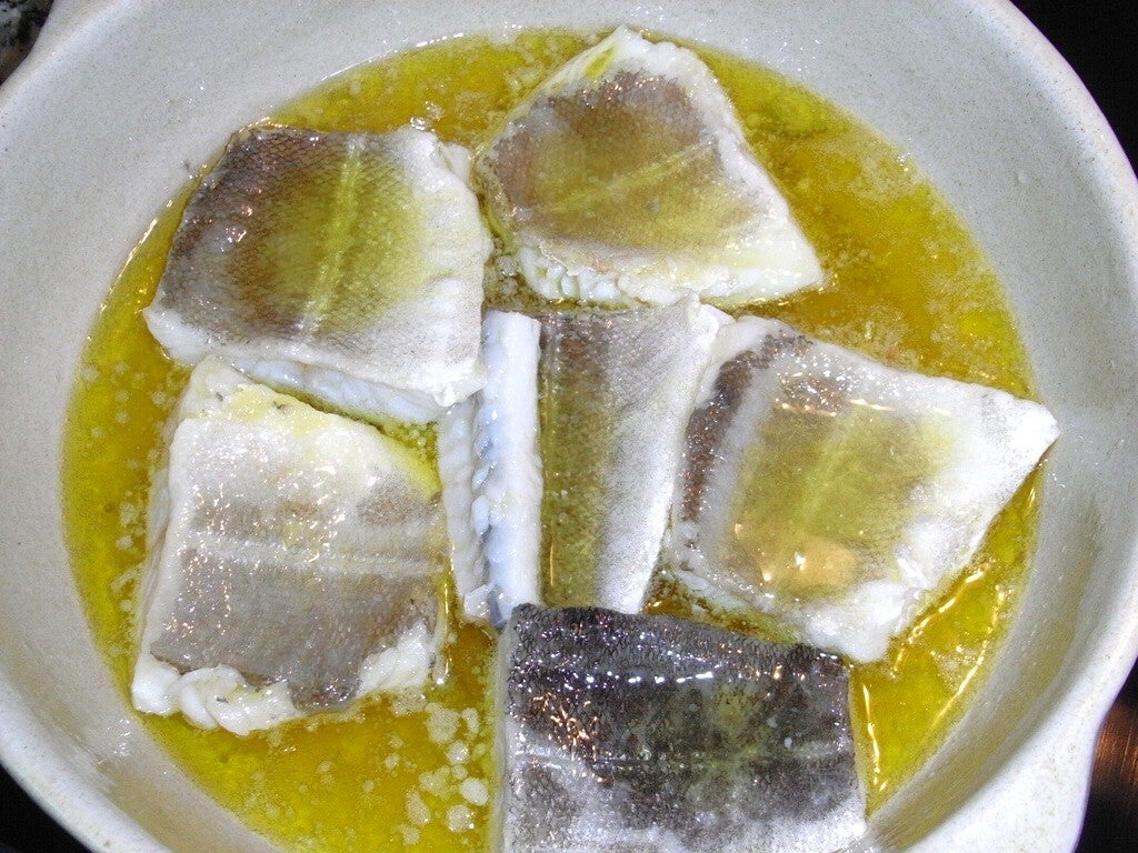Lomos de bacalao en cazuela de barro con aceite de oliva y ajo, momento previo a ligar el pil-pil