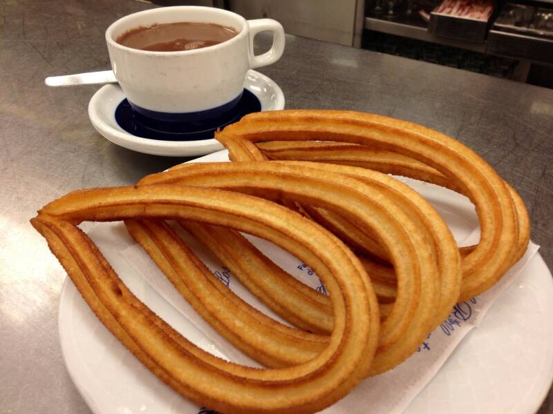 Chocolate espeso a la taza con churros de lazo sobre la barra, dulce típico de Madrid.