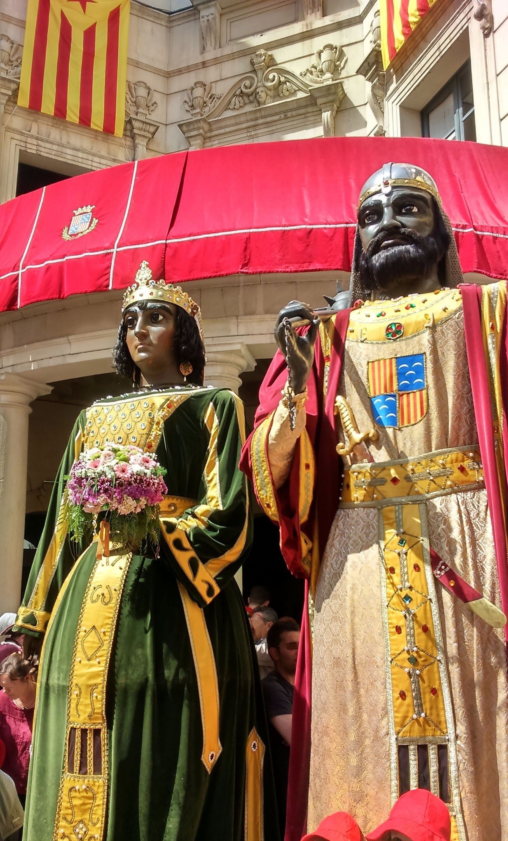 Els Gegants Nous de la Patum de Berga, la pareja de gigantes rey y reina, en contrapicado bajo el dosel rojo de la plaza de Sant Pere