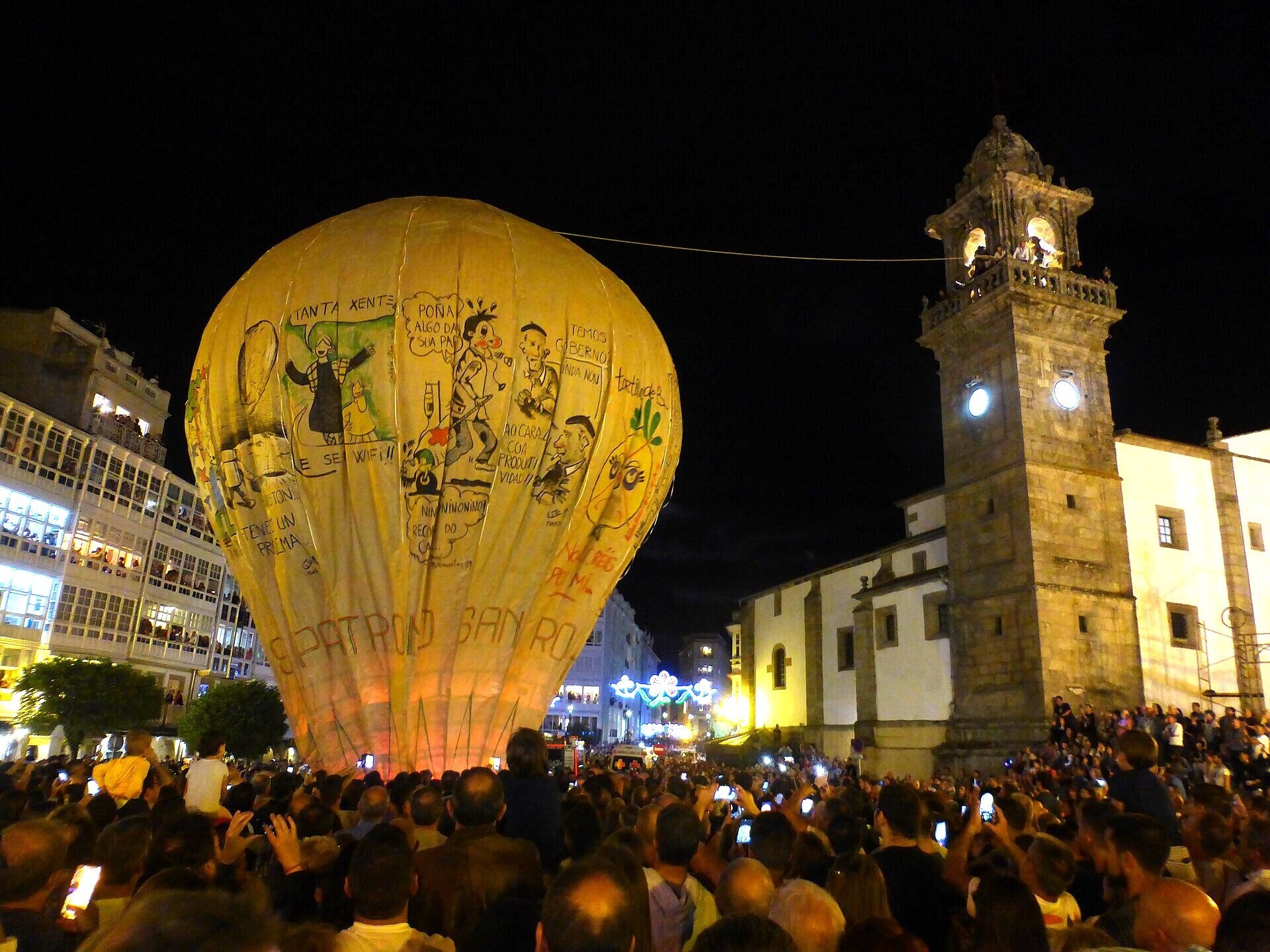 El Globo de Betanzos, aeróstato de papel, inflándose de noche junto al campanario de Santo Domingo durante las Fiestas de San Roque
