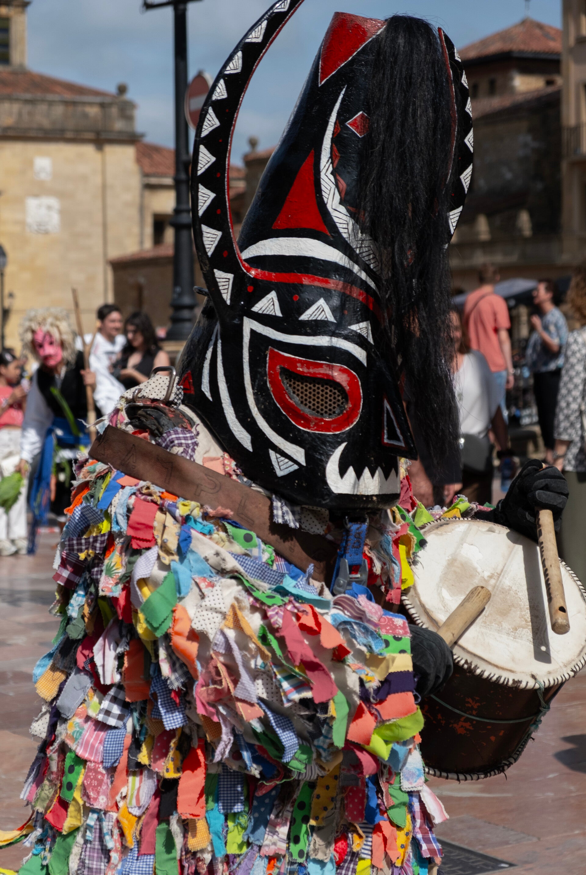 Jarramplas de Piornal con la máscara de cuernos con crines, traje de cintas de colores y con el tamboril, en el desfile.