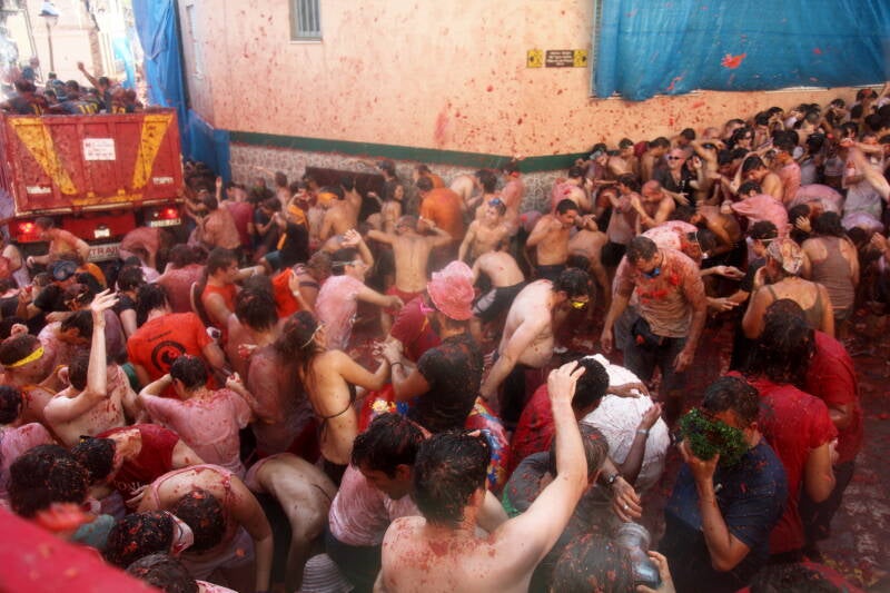 Participantes en La Tomatina lanzando tomates en las calles de Buñol, Valencia