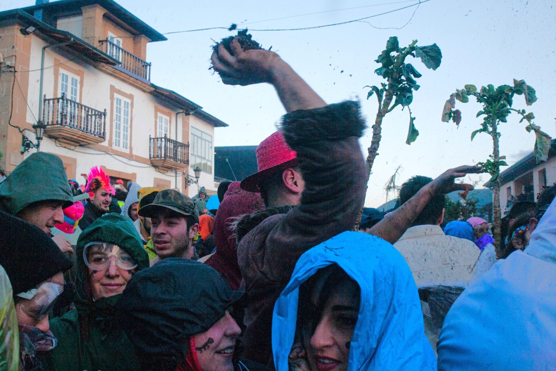 Un hombre lanza un puñado de tierra con hormigas sobre la multitud durante «Las Hormigas» del Entroido de Laza.