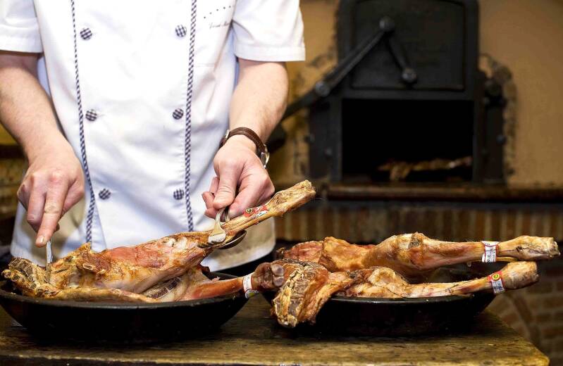 Cocinero sirviendo lechazo asado tradicional de Castilla y León