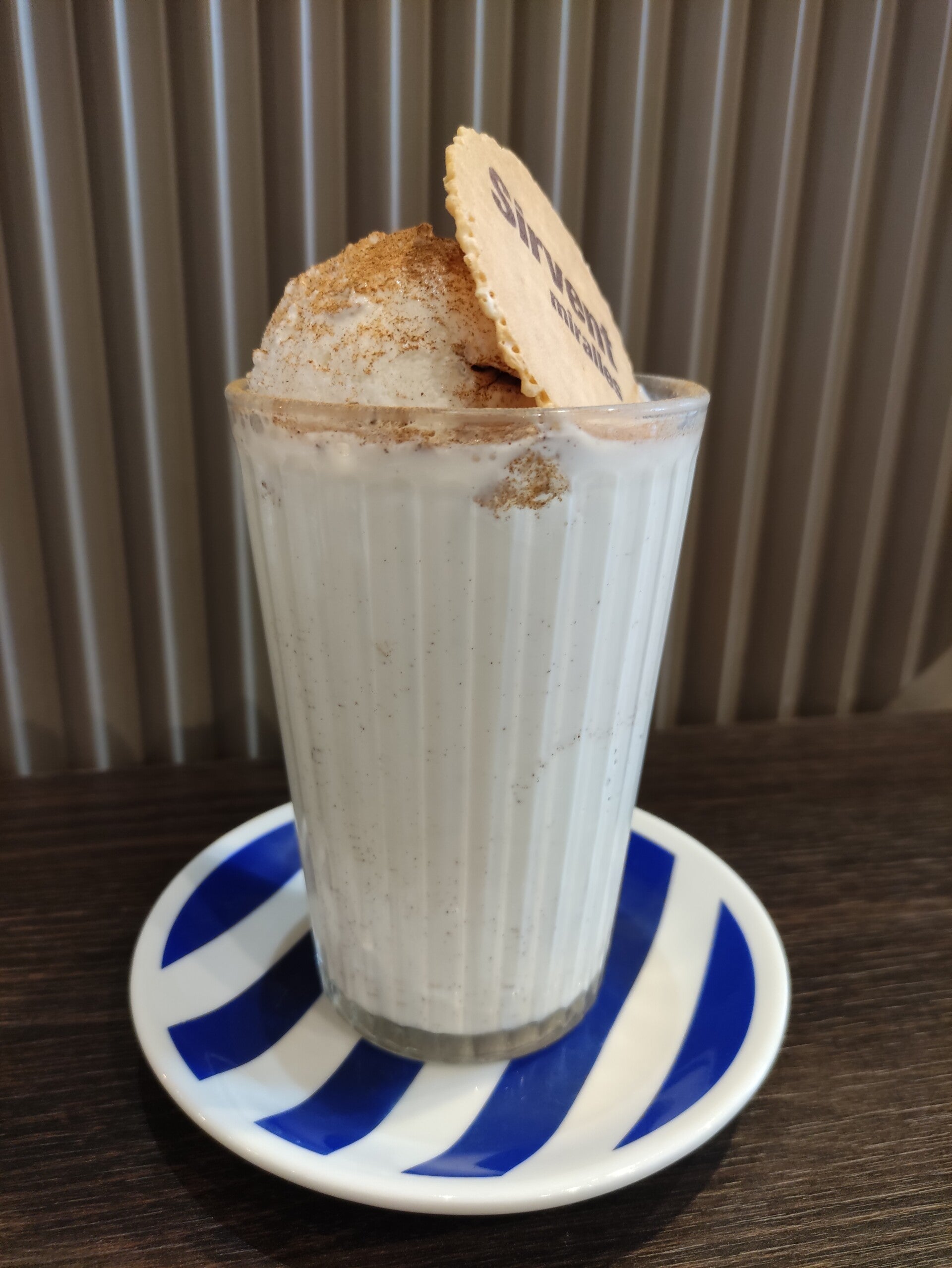 Llet merengada servida en vaso alto con canela espolvoreada y un barquillo