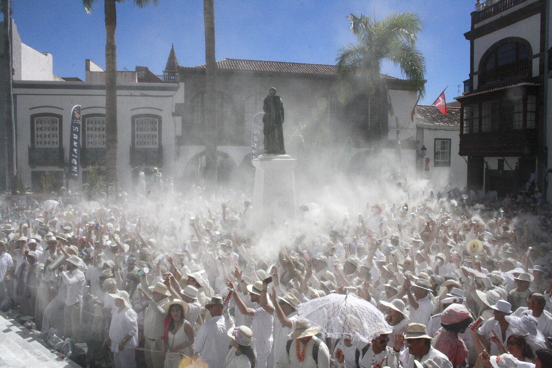 Multitud vestida de blanco entre polvos de talco en el Día de Los Indianos, plaza de España de Santa Cruz de La Palma.