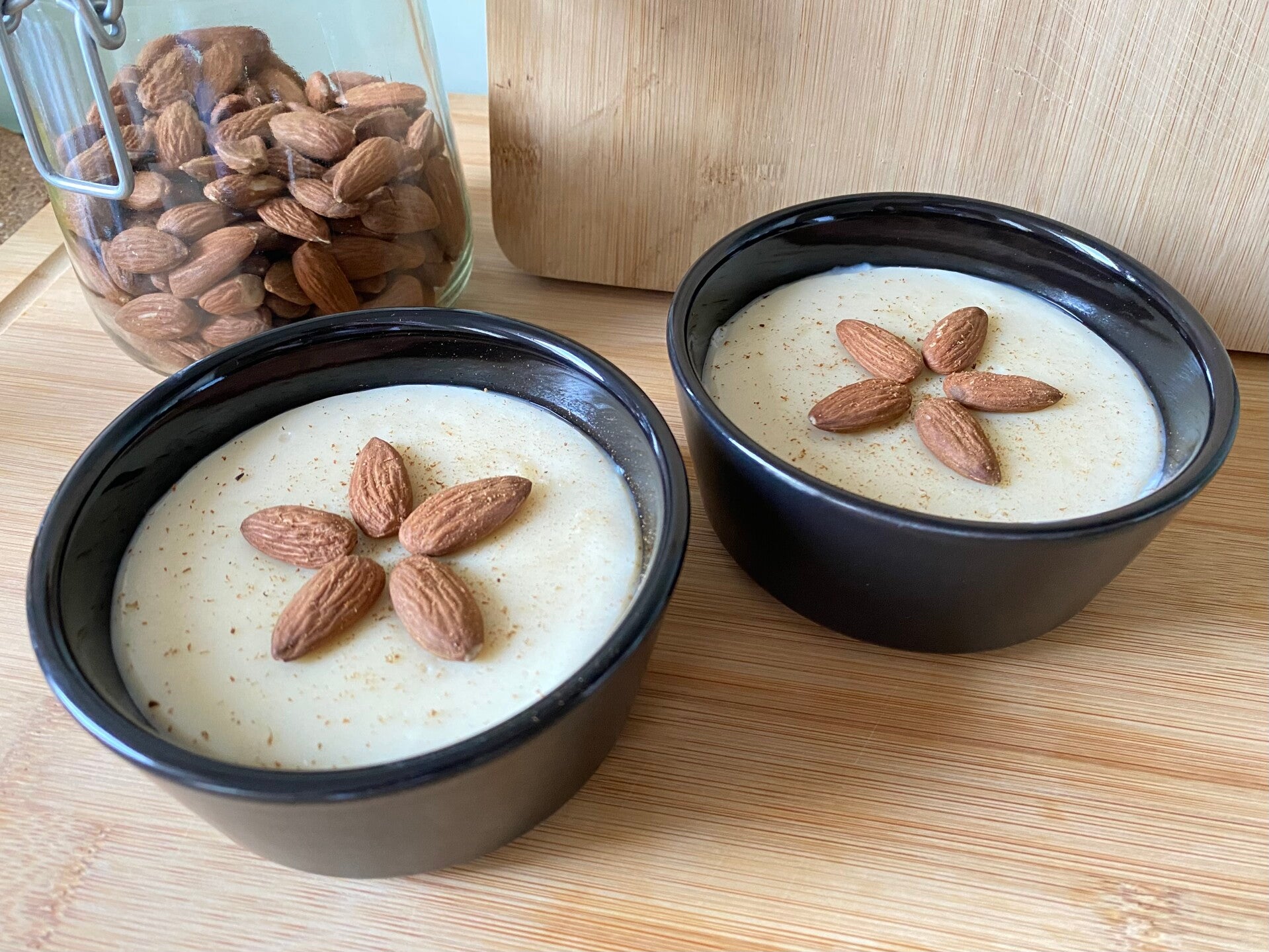 Dos raciones de menjar blanc de Reus, una crema blanca de almendra, decoradas con almendras, canela y vainilla en polvo