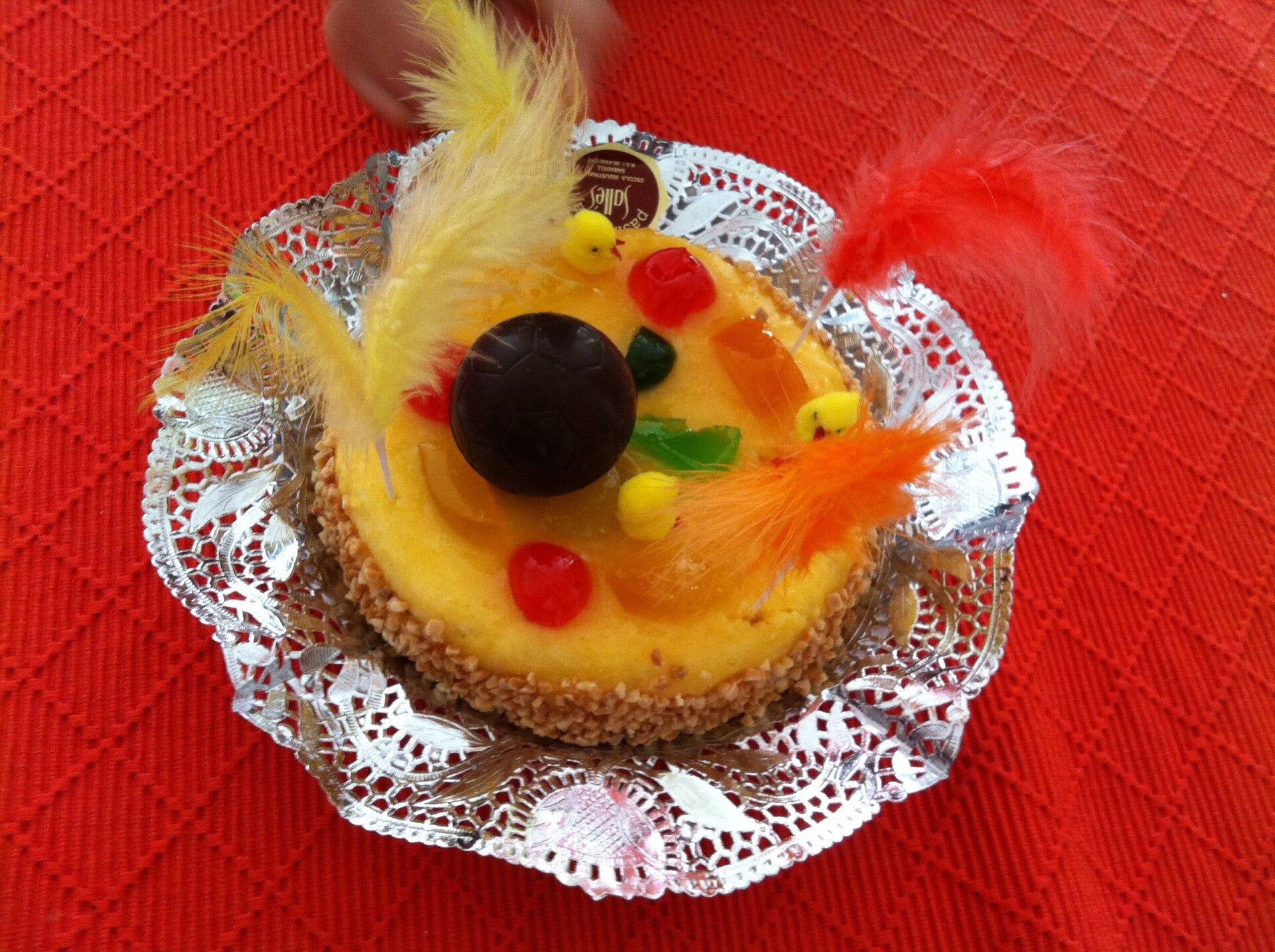 Mona de Pascua catalana con huevos y figuras de chocolate, confitados y plumas de colores, el pastel del Lunes de Pascua