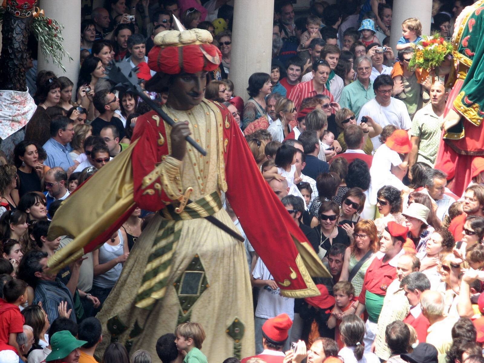 Un gegant de la Patum de Berga, con turbante y maza al hombro, bailando entre la multitud que llena la plaza durante el Corpus