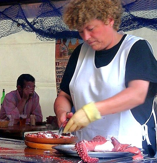 Una pulpeira corta pulpo á feira en una feria gallega