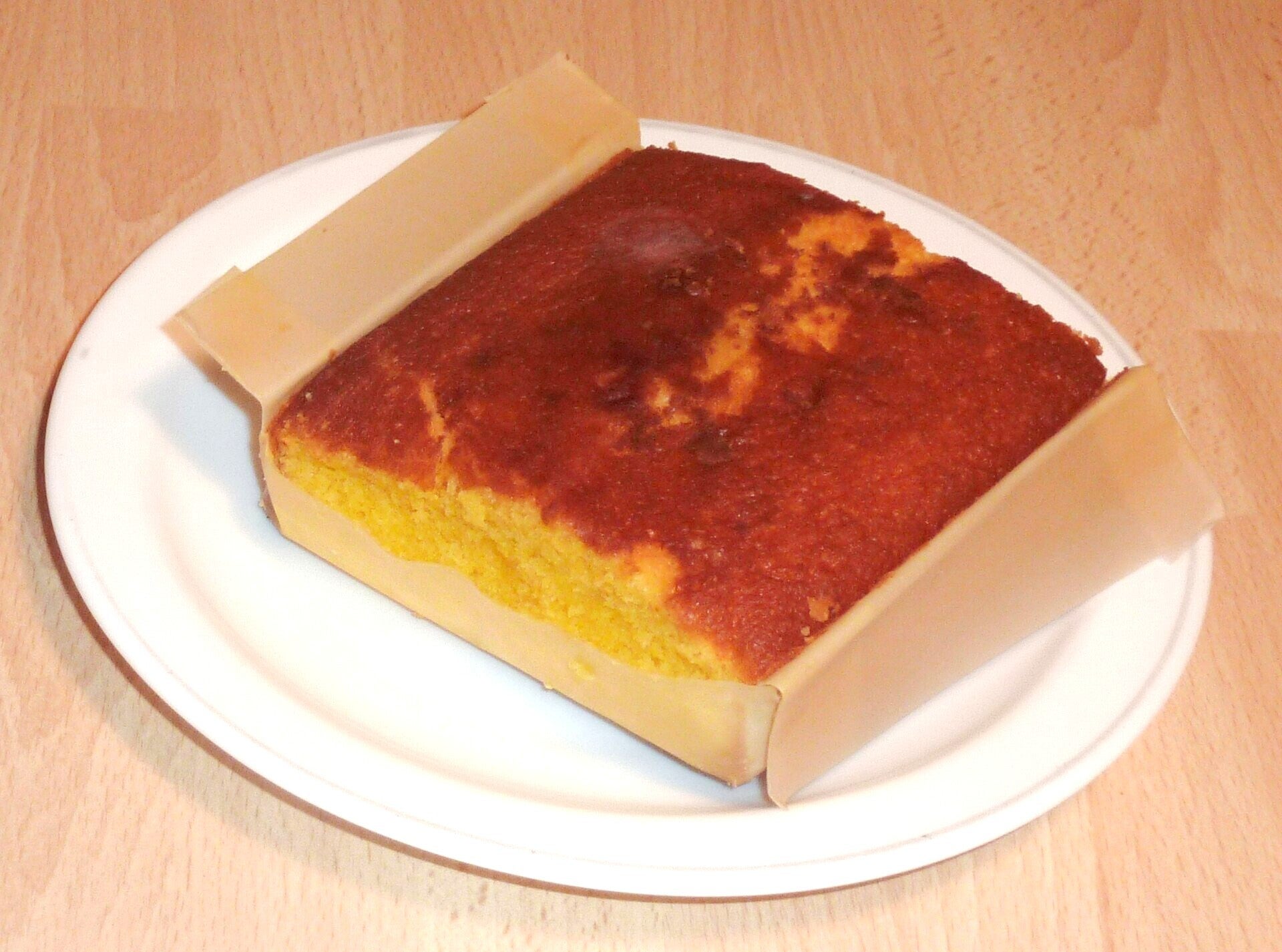 Sobao pasiego en su envoltorio de papel, con la miga dorada y esponjosa, dulce típico de Cantabria