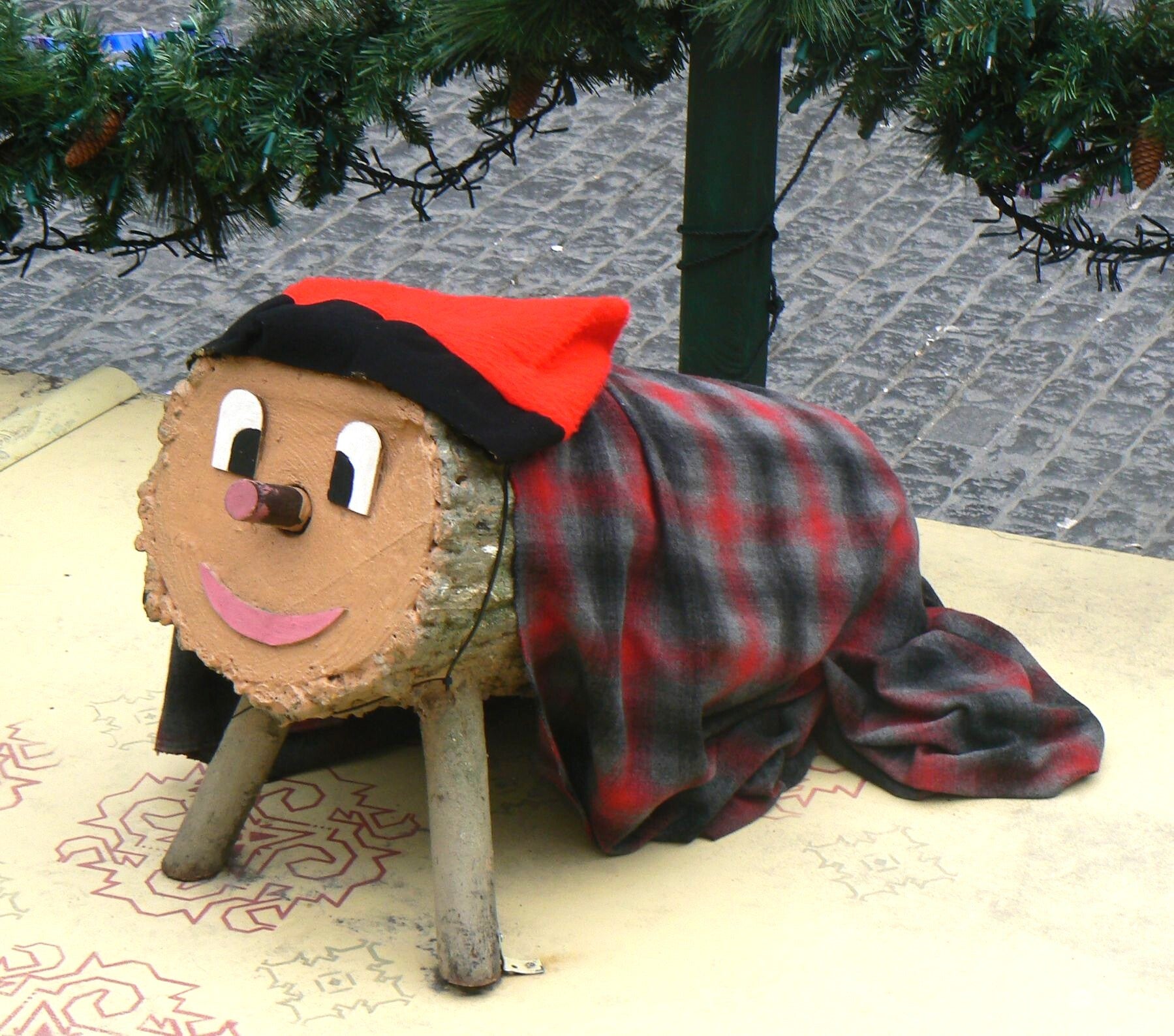 Tió de Nadal, tronco típico catalán con cara sonriente y patas, tapado con su manta y su barretina, que entrega dulces y regalos.