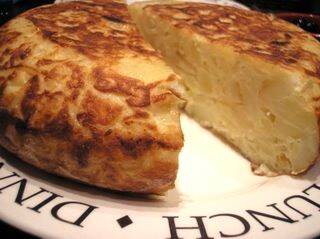 Tortilla de patatas cortada mostrando el interior jugoso, clásico de la barra madrileña y de toda España.