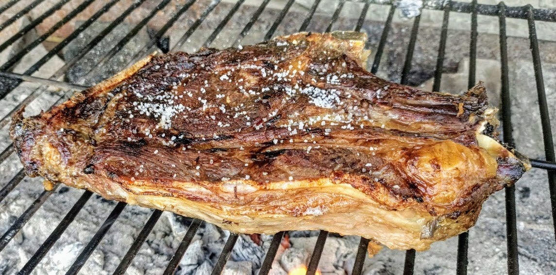 Txuleta de vaca vieja en la parrilla sobre brasas, con costra tostada y sal gorda