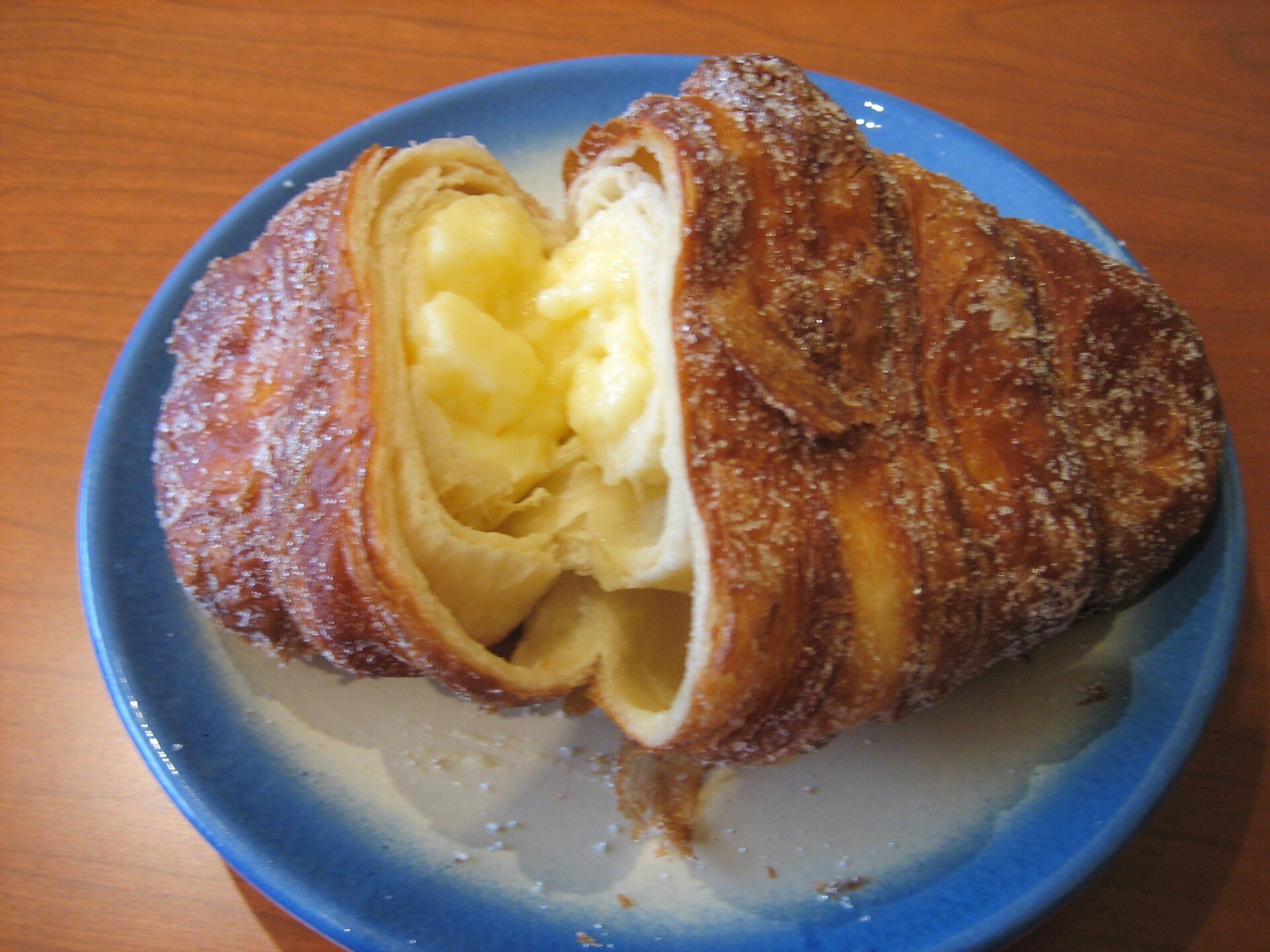 Xuixo de Girona partido, con el relleno de crema pastelera a la vista, la masa frita y rebozada en azúcar