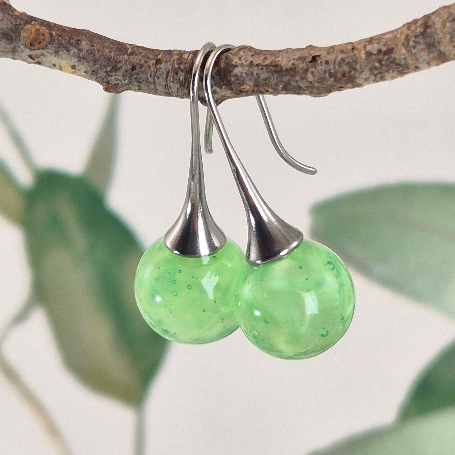 Trompetvormige glazen oorbellen met bolletjes van zacht groen glas met pearl-effect