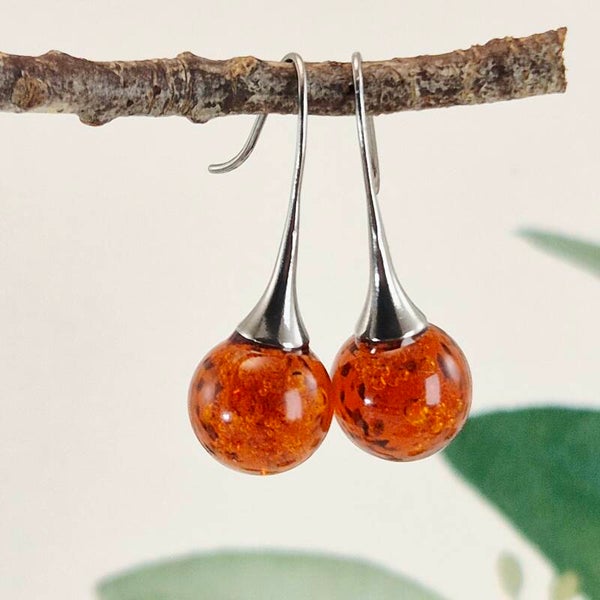 Trompetvormige glazen oorbellen met bolletjes van donker amberkleurig glas met luchtbelletjes