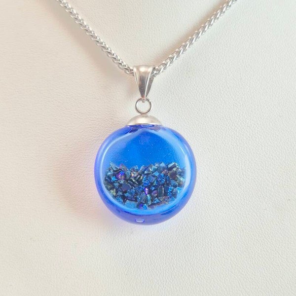 Transparante holle blauwe glazen hanger met gekleurde steentjes erin