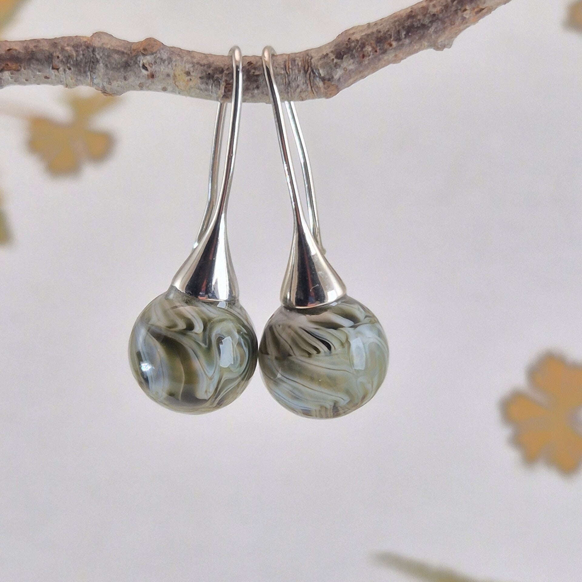 Trompet oorbellen met bolletjes van groen-grijs en wit glas met streeppatroon