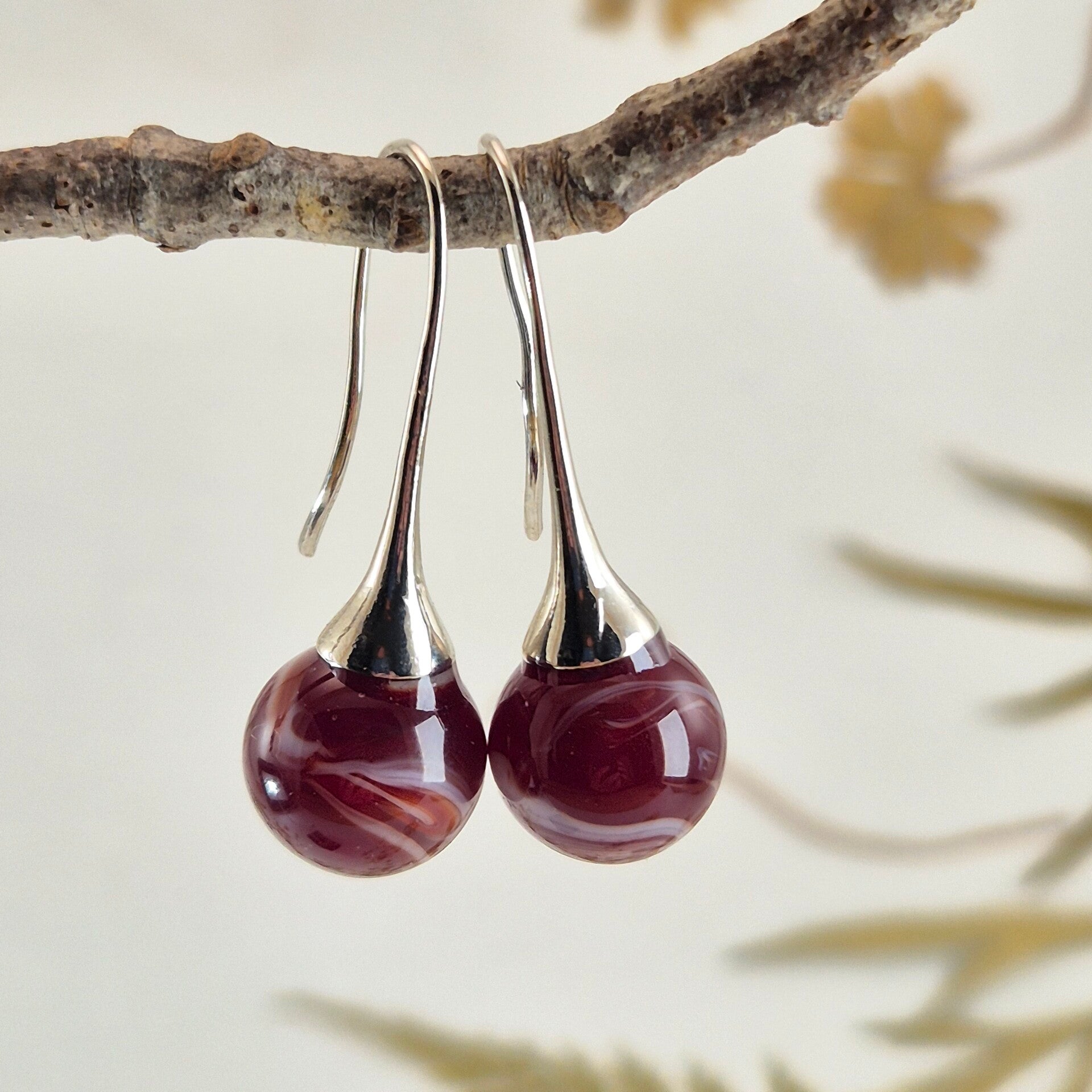 Trompet oorbellen met bolletjes van donkerrood met wit glas