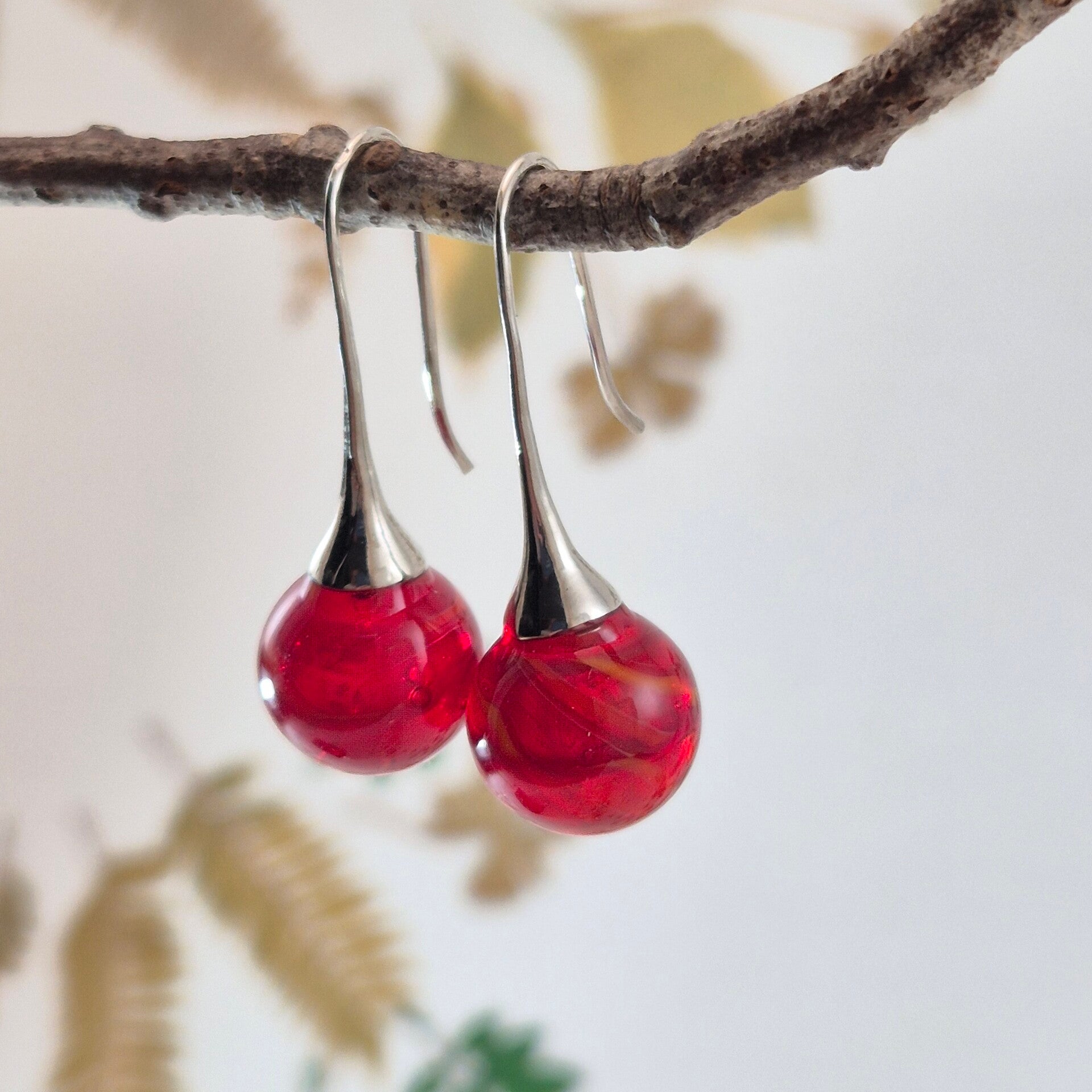 Trompet oorbellen met bolletjes van transparant rood glas met oranje/zacht geel streeppatroon
