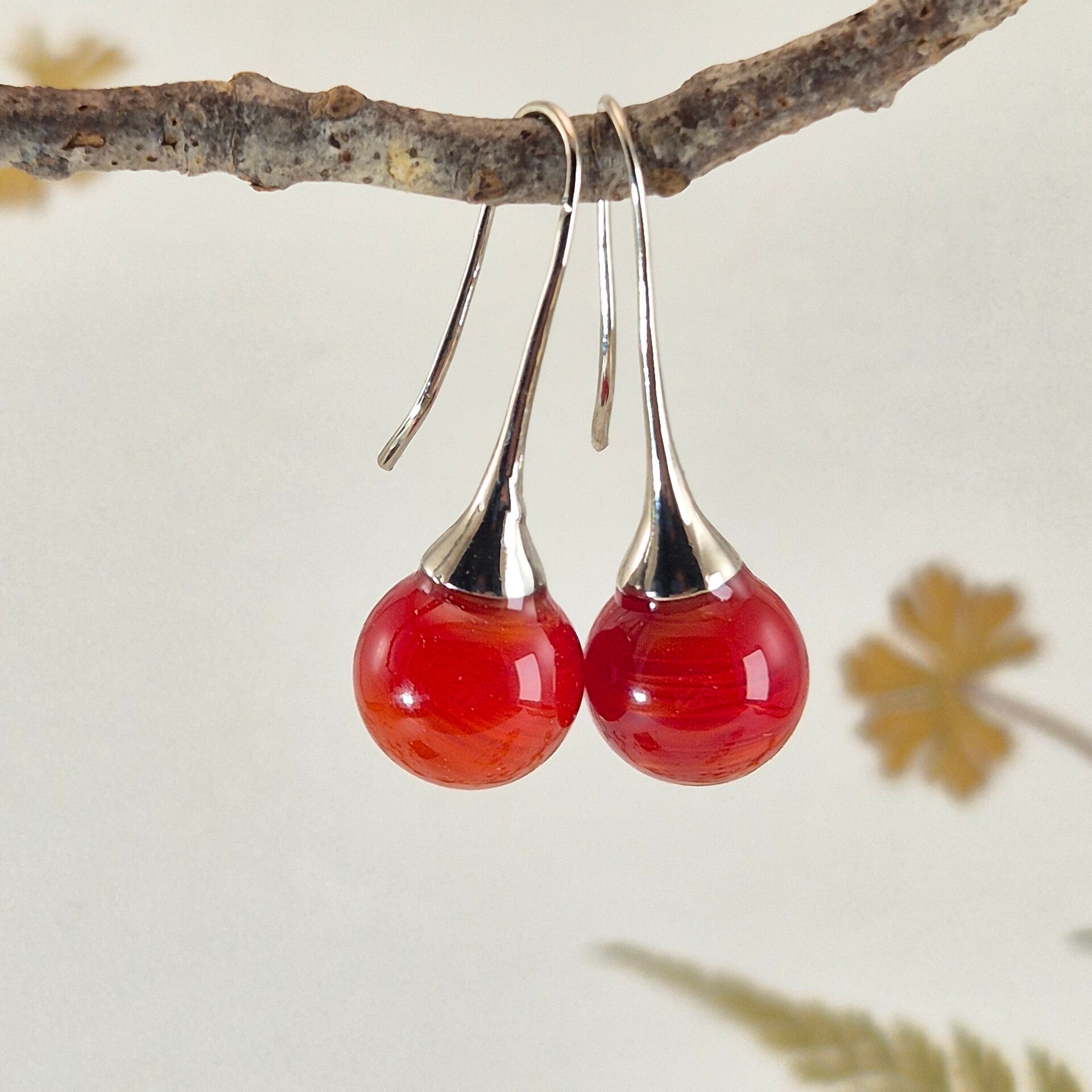 Trompet oorbellen met bolletjes van rood/oranje glas met iets streeppatroon