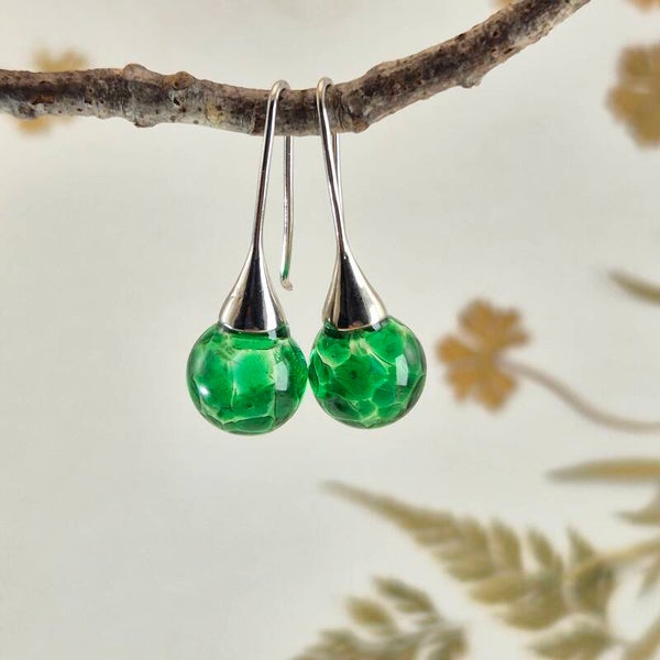 Trompet oorbellen met bolletjes van transparant glas met groen stip-patroon