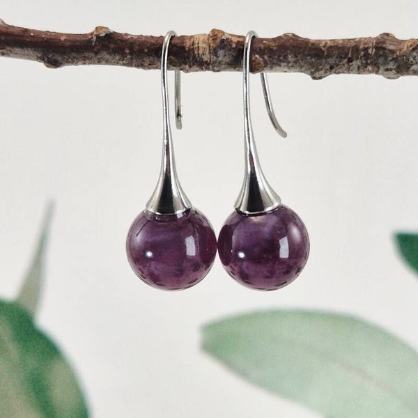 Trompetvormige glazen oorbellen met bolletjes van donker paars glas met pearl-effect